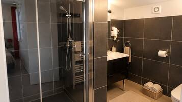 A modern bathroom with a glass-enclosed shower, a white sink, and a toilet.