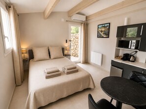 Quarto com cama, abajures, escrivaninha com micro-ondas e vista para o exterior.