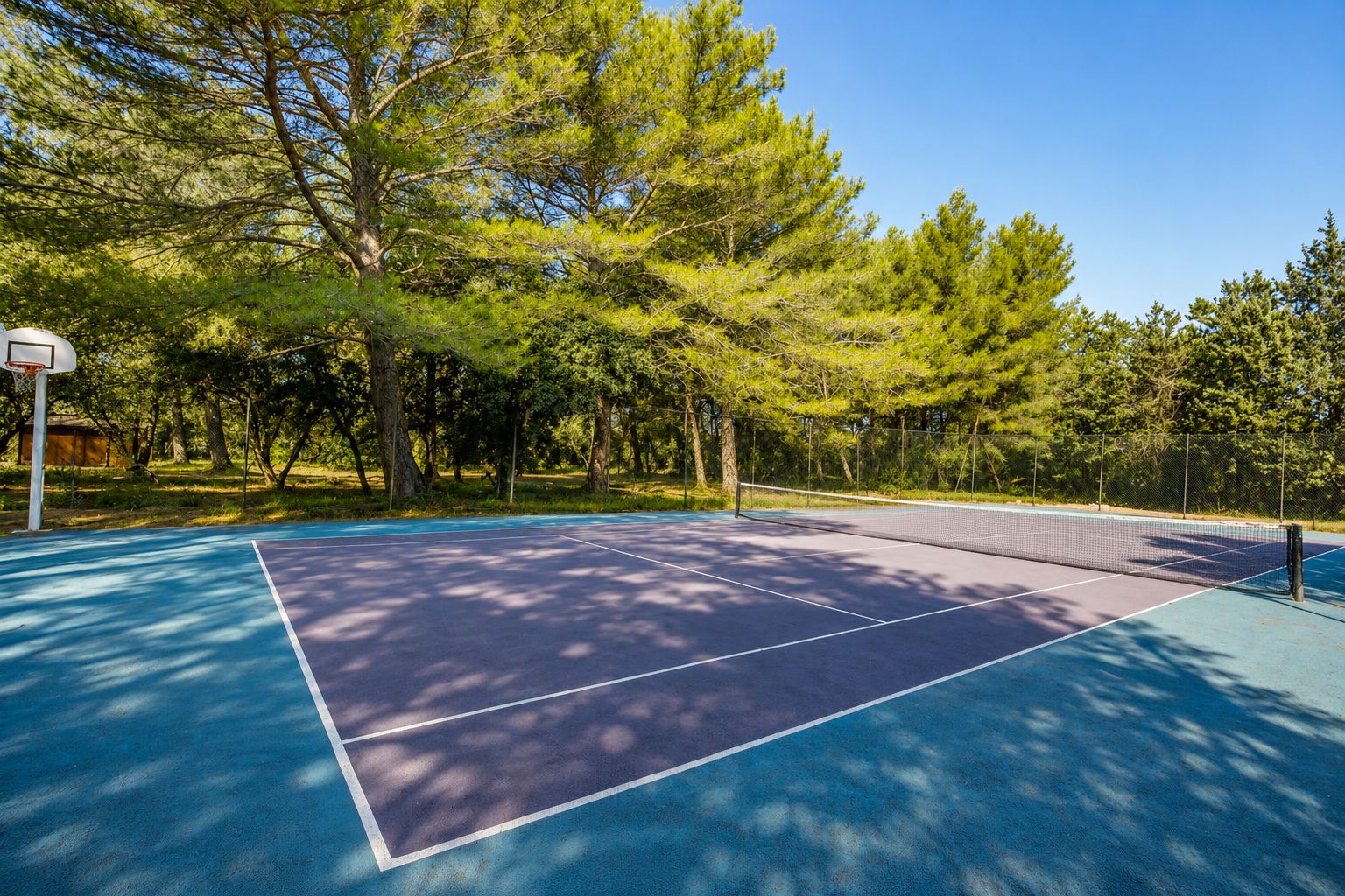 An outdoor basketball court surrounded by trees.