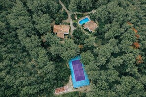 An aerial view of a property with a tennis court, two houses, and dense forest. - Le Domaine d'Alèzen (Grans)