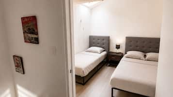 A bedroom with two beds, a nightstand, and a wall-mounted light.