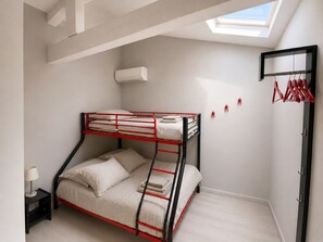 A bunk bed room with a skylight, a small bedside table, and a clothing rack. - Le Domaine d'Alèzen (Grans)