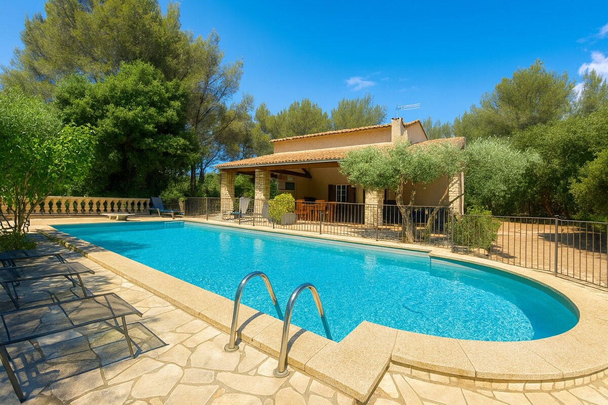 A swimming pool with a stone deck, surrounded by a fence and trees.