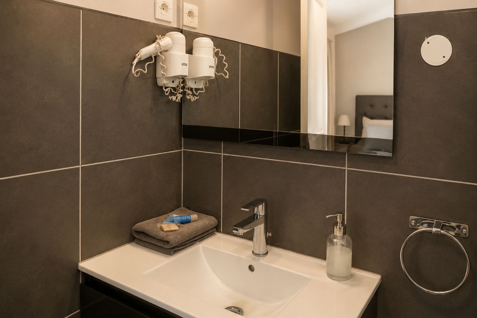 A modern bathroom with a white sink, a mirror, and a towel rack.