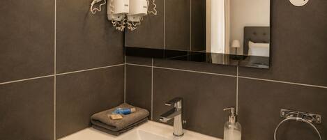 A modern bathroom with a white sink, a mirror, and a towel rack.
