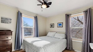 A bedroom with a bed, a dresser, a ceiling fan, and two framed pictures on the wall. - Charming 1940's Cottage in central location (Rapid City)