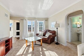 A living room with a glass-top coffee table, a brown leather sofa, and a floor lamp.