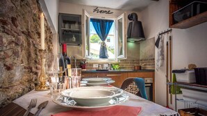 Una cocina acogedora con pared de piedra, una ventana con cortinas azules y un letrero que dice 'Home' sobre los armarios.