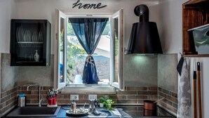 Una cocina con ventana, una campana extractora negra y un letrero que dice 'hogar' sobre la ventana.