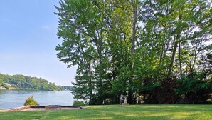 A blue and red disc golf disc golf hole with the text "DH-PENHOY" on it, set in a grassy area with trees and a lake in the background.
