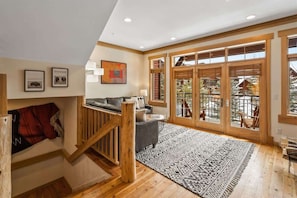 A spacious living area with a wooden staircase, a sofa, and a patterned rug.