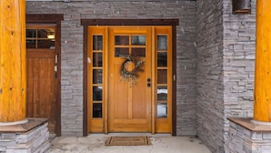 A wooden front door with a wreath, flanked by stone walls and wooden pillars. - Lodge-style Condo in the Heart of Big Sky (Big Sky)