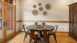 A dining area with a round table, six chairs, and decorative wall art. - Lodge-style Condo in the Heart of Big Sky (Big Sky)