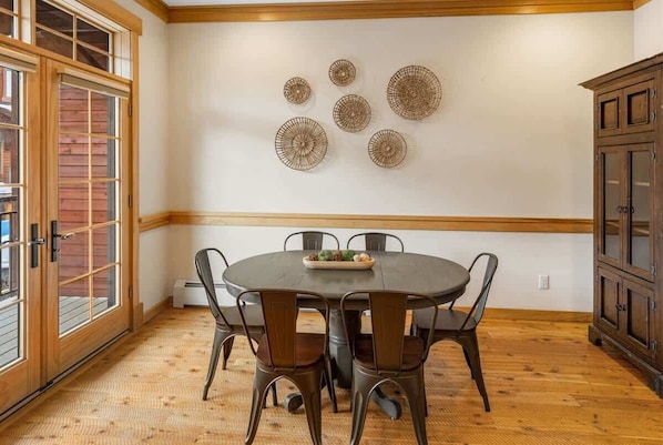 A dining area with a round table, six chairs, and decorative wall art.