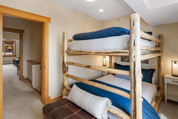 A bunk bed room with a wooden headboard, a bedside table, and a lamp.