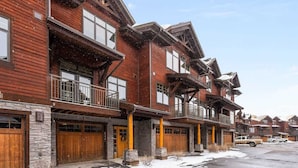 A row of wooden multi-story buildings with balconies and garage doors. - Lodge-style Condo in the Heart of Big Sky (Big Sky)