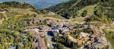 Aerial view of a mountain resort village nestled in forested valleys with scenic alpine surroundings and ski terrain.