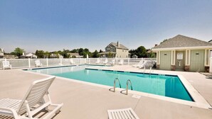 A rectangular pool with white lounge chairs and a small building with a sign. - Beautiful spacious family friendly home in Rehoboth Beach with Pool (Rehoboth Beach)