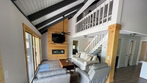 A spacious living area with a high ceiling, a built-in fireplace, a sofa set, and a staircase leading to an upper level. - Breathtaking lake views, steps from beach, golf, and clubhouse. Renovated home! (Big Canoe)