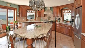 A spacious kitchen with a large island, wooden cabinets, and stainless steel appliances. - Entire Waterfront Home with Panoramic Views of the Bay and Private Beach (Mastic Beach)