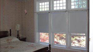 A bedroom with a bed, a nightstand, a lamp, and a window with a view of trees. - Spacious Updated Victorian, A/C, Walk to Beach, Close to Town  (Narragansett)