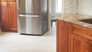 A kitchen with wooden cabinets, a stainless steel refrigerator, and a tiled floor. - Spacious Updated Victorian, A/C, Walk to Beach, Close to Town  (Narragansett)