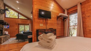 Un accogliente camera da letto con un letto, un camino, una TV e una parete in pietra.