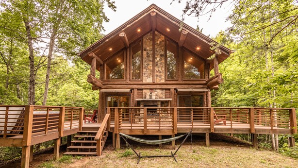 A wooden cabin with a stone fireplace, wooden deck, and a hammock. - Watershed 1 - Modern-Rustic, Luxury, One King Bedroom Cabin (Bryson City)