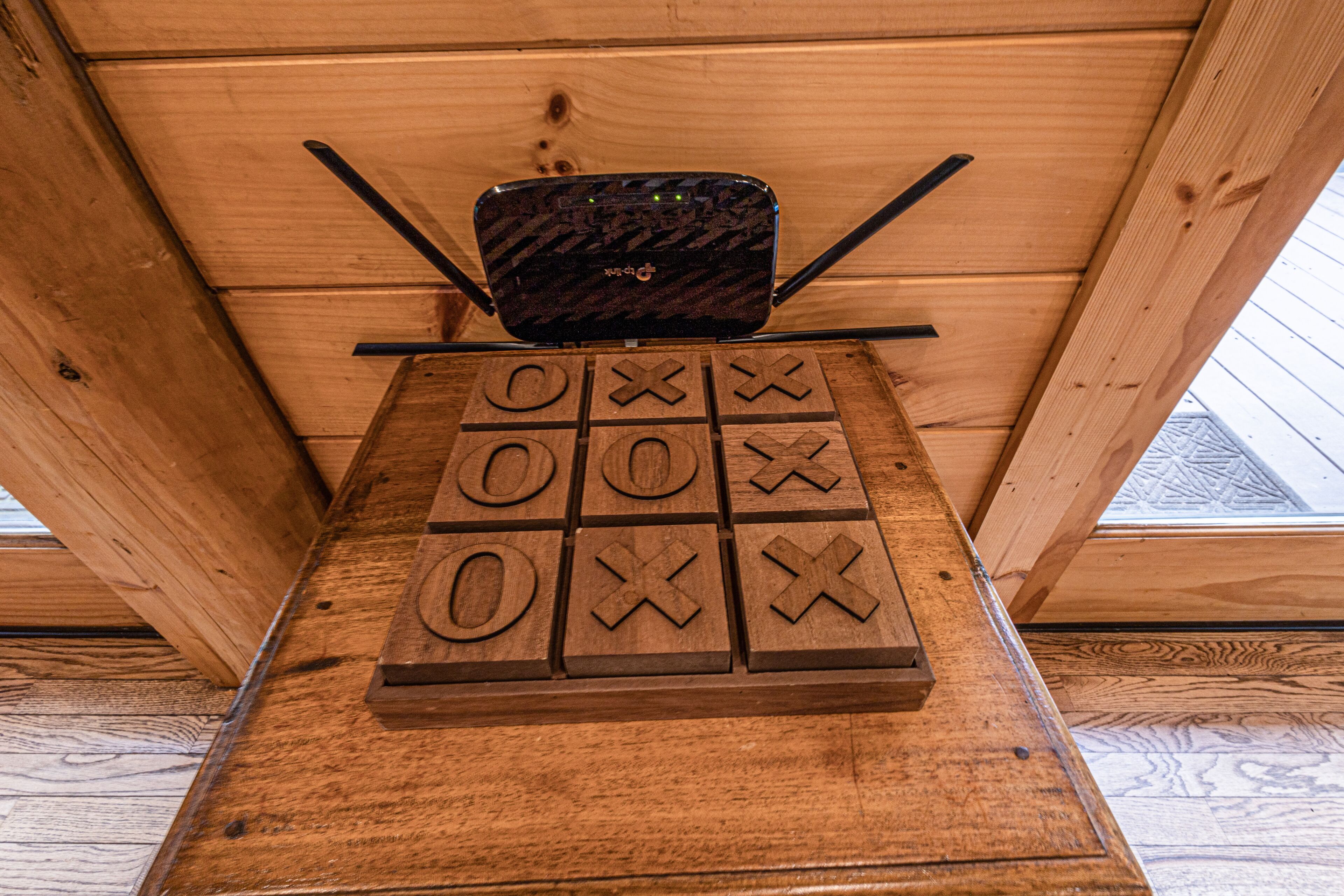 A wooden board game with a black electronic device on top, set against a wooden wall.