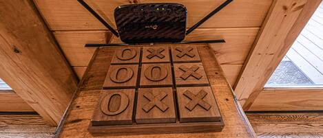 A wooden board game with a black electronic device on top, set against a wooden wall.