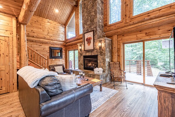 Cozy cabin interior with a warm fireplace, comfortable seating, and scenic views of the surrounding forest.