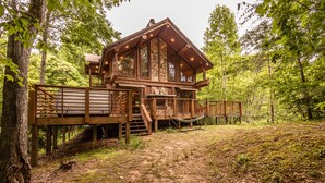 A wooden cabin with a deck, surrounded by trees. - Watershed 1 - Modern-Rustic, Luxury, One King Bedroom Cabin (Bryson City)