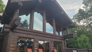 Un edificio de estilo cabaña de madera con un jacuzzi y mobiliario exterior.