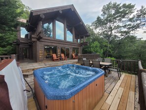 Eine Holzhütte mit Whirlpool auf einer Terrasse, umgeben von Bäumen.