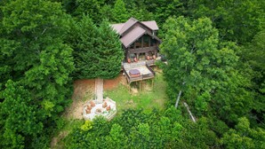 Una cabaña de madera con terraza, rodeada de un bosque frondoso.