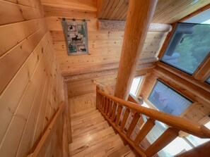 A wooden staircase with a handrail, wooden walls, and a window with a view of greenery. - Watershed 8 - Breathtaking Views from Hot Tub and Firepit (Bryson City)