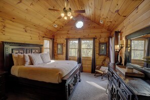 Een slaapkamer in een houten hutje, met een bed, nachtkastje, stoel en een kast.