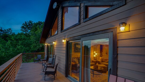 Et moderne hus med terrasse, store skydedøre og udendørs møbler.