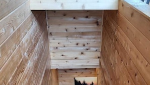 Una escalera de madera que ofrece vista del bosque a través de una abertura en la parte superior.