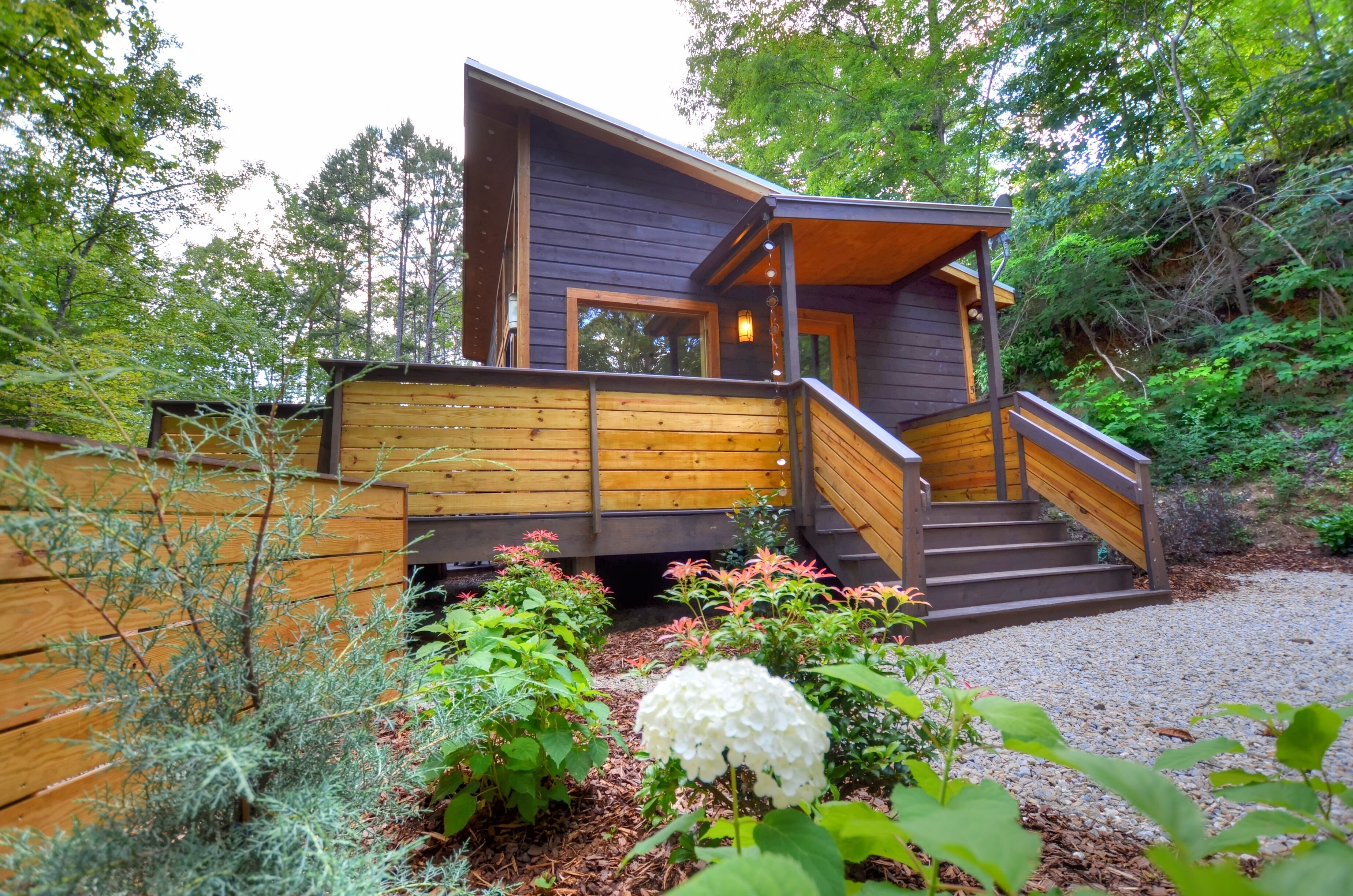 A modern wooden cabin with a wooden deck and stairs leading to the entrance.