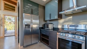 Una cocina moderna con electrodomésticos de acero inoxidable, armarios oscuros y un ventanal grande.