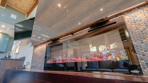 Un interior moderno con un amplio ventanal, techo de madera y un área de descanso con vistas al exterior.