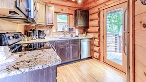 A log cabin kitchen with granite countertops, stainless steel appliances, and a wooden floor. - Fontana View 1 - Ridgetop - Gated Community (Almond)
