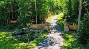Un sentier qui traverse une zone boisée, avec un banc en bois et un panneau indiquant « Zone de captage ».