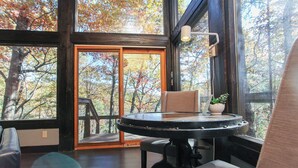 Ein Zimmer mit einem großen Fenster, einem runden Tisch und einem Stuhl.