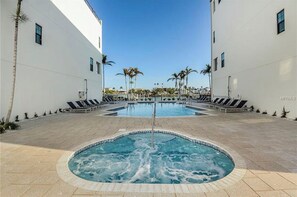 Relax by the pool with a hot tub and lounge chairs surrounded by lush greenery.