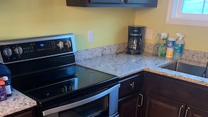 A kitchen with a black stove, stainless steel oven, and granite countertop.
