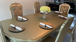 A dining table with ornate chairs, a vase with flowers, and a modern chandelier.