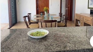 A dining area with a round table, chairs, and a bowl of food on a granite countertop. - SanCrisanto House (San Crisanto)