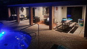 Un patio al aire libre con un jacuzzi, asientos y una mesa.
